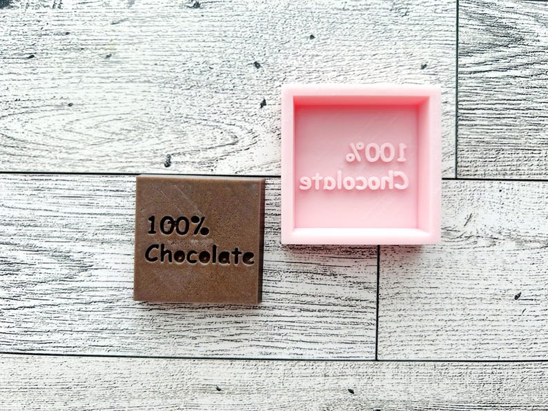 May include: Two chocolate bar moulds, one pink and one brown, both with the text "100% Chocolate" on them.