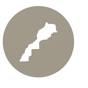 May include: A circular emblem featuring a solid taupe background with a white silhouette of the map of Morocco centered within the circle. The design is flat and graphic, showcasing the distinct geographical outline of the country in white.