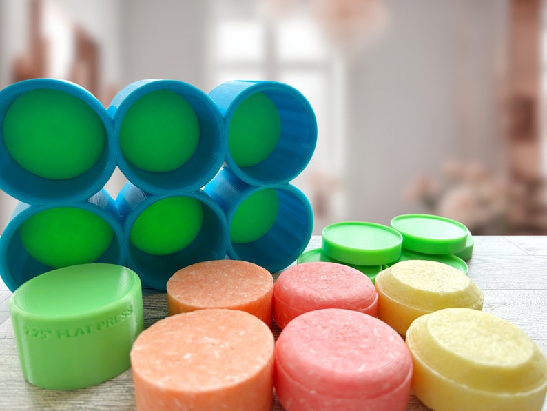 Pu&ograve; includere: Una collezione di saponette rotonde e colorate e stampi cilindrici. I saponi sono nelle tonalit&agrave; dell'arancione, del rosa e del giallo, con stampi verdi e blu. Un sapone verde ha il testo "2.25" FLAT PRESS".