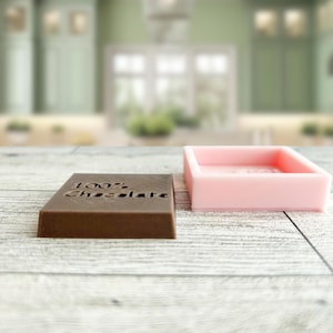 May include: Two rectangular silicone moulds, one brown and one pink. The brown mould has the words "100% Chocolate" embossed on the top.