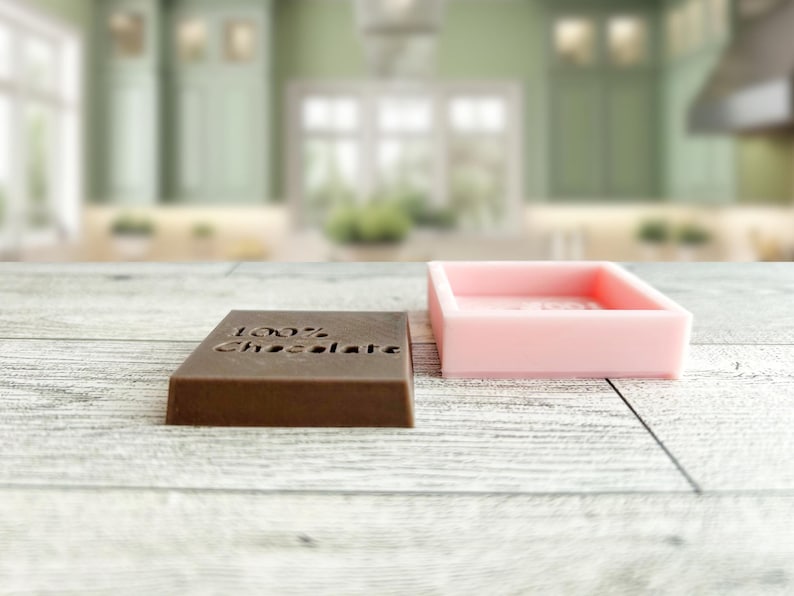 May include: Two rectangular silicone moulds, one brown and one pink. The brown mould has the words "100% Chocolate" embossed on the top.