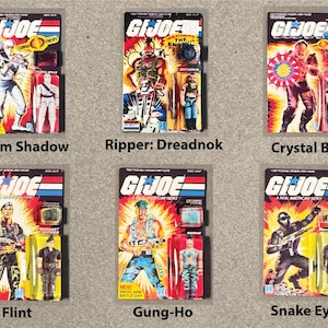 May include: Six vintage G.I. Joe action figures on their original packaging. The figures include Storm Shadow, Ripper: Dreadnok, Crystal Ball, Flint, Gung-Ho, and Snake Eyes. Each package features vibrant colors and character art.