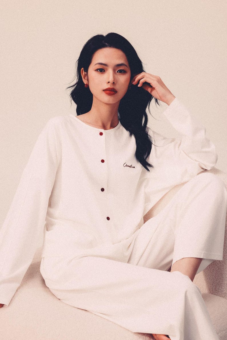 May include: A white long-sleeved pajama top with red buttons and the word "Camelia" embroidered on the chest.