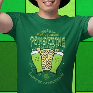 Sipping Guinness, Pondering Galaxies. Happy St. Patrick's day. The Perfect Unisex T-Shirt for the Irish Astrophysics Lover.
