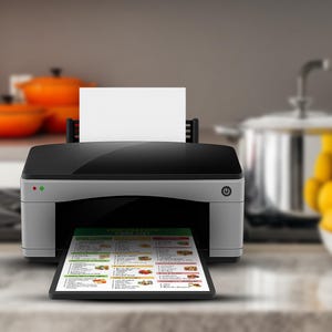 Pu&ograve; includere: Una stampante nera e grigia stampa un menu colorato su carta bianca. Il menu presenta vari piatti con immagini. La stampante &egrave; su un piano di lavoro della cucina, con pentole arancioni e una pentola in acciaio inossidabile sullo sfondo.