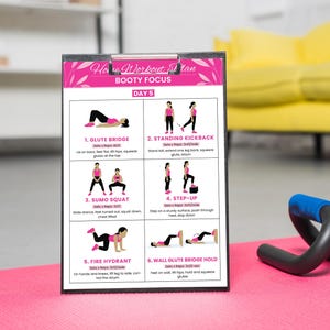 Puede incluir: Un plan de entrenamiento en casa rosa y blanco titulado "Booty Focus" para el d&iacute;a 5. El plan incluye seis ejercicios con ilustraciones: Glute Bridge, Standing Kickback, Sumo Squat, Step-Up, Fire Hydrant y Wall Glute Bridge Hold. El plan est&aacute; en una carpeta negra.