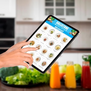 Peut inclure: Une tablette num&eacute;rique affichant un plan de repas pour les personnes souffrant de calculs biliaires. Le plan comprend une vari&eacute;t&eacute; d'options de petit-d&eacute;jeuner, notamment des toasts &agrave; l'avocat, des flocons d'avoine et des fruits. La tablette est tenue par une main dans un environnement de cuisine.