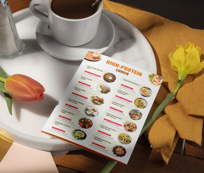 Może przedstawiać: Drukowalne menu z listą opcji lunchowych bogatych w białko. Menu zawiera takie dania jak kanapka z sałatką jajeczną, sałatka z makaronem i kurczakiem oraz sałatka z makaronem, łososiem i krewetkami. Menu znajduje się na białym talerzu z filiżanką kawy i ż&oacute;łtym kwiatem.
