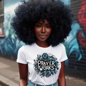 May include: A white t-shirt with a blue and black graphic design that says "PRAYER WORKS" in a stylized font.