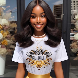May include: A white t-shirt with a black and gold graphic design featuring the word "BEHOLD!" in gold lettering. The shirt has short sleeves and a crew neck.