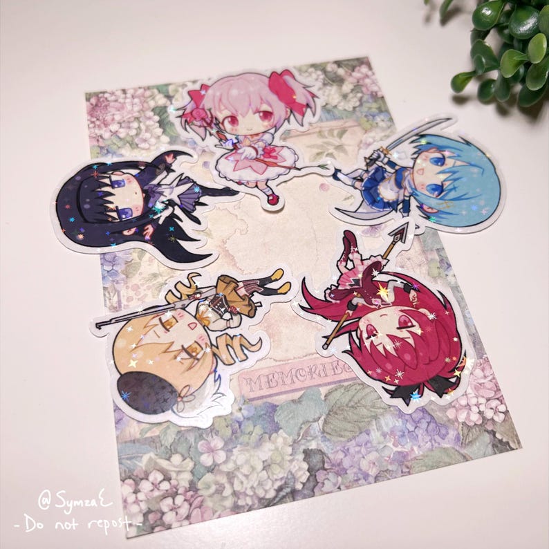 May include: Five holographic stickers featuring anime characters. The stickers are on a white background with a floral pattern. The characters are all girls with different colored hair and outfits. The stickers are all in a chibi style, which is a Japanese style of drawing characters with large heads and small bodies.