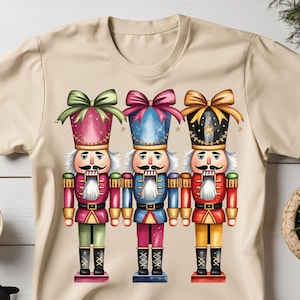 May include: Three nutcracker figurines with colourful hats and bows. The nutcrackers are wearing red, blue, and green uniforms with gold accents. They are standing in a row on a beige background.