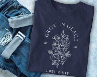 May include: Navy blue t-shirt with a white floral design and the text "Grow in Grace" with a double line on either side of the text. Below the floral design is the text "2 Peter 3:18".