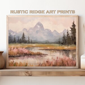 May include: A framed painting depicting a mountainous landscape with a lake in the foreground. The mountains are painted in shades of blue and purple, and the lake is a light blue with reflections of the mountains. The foreground is a field of grass and wildflowers.