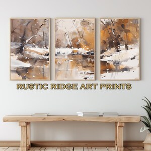 May include: Three framed watercolour paintings depicting a landscape scene with brown, white and yellow hues. The paintings are arranged in a row on a white wall. The text "RUSTIC RIDGE ART PRINTS" is displayed below the paintings.