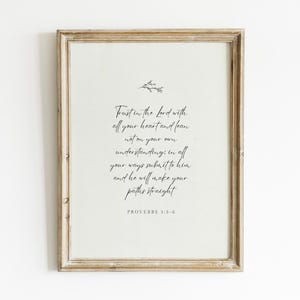 May include: A framed print with a light beige background and a distressed wooden frame. The artwork displays elegant script with the text "Trust in the Lord with all your heart and lean not on your own understanding..." and the reference "PROVERBS 3:5-6".