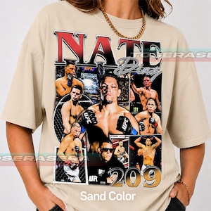 May include: A sand-colored t-shirt featuring a large graphic print of mixed martial artist Nate Diaz. The design includes multiple action photos of the fighter, the text NATE DIAZ in bold red and black, and the number 209 in large gold font.