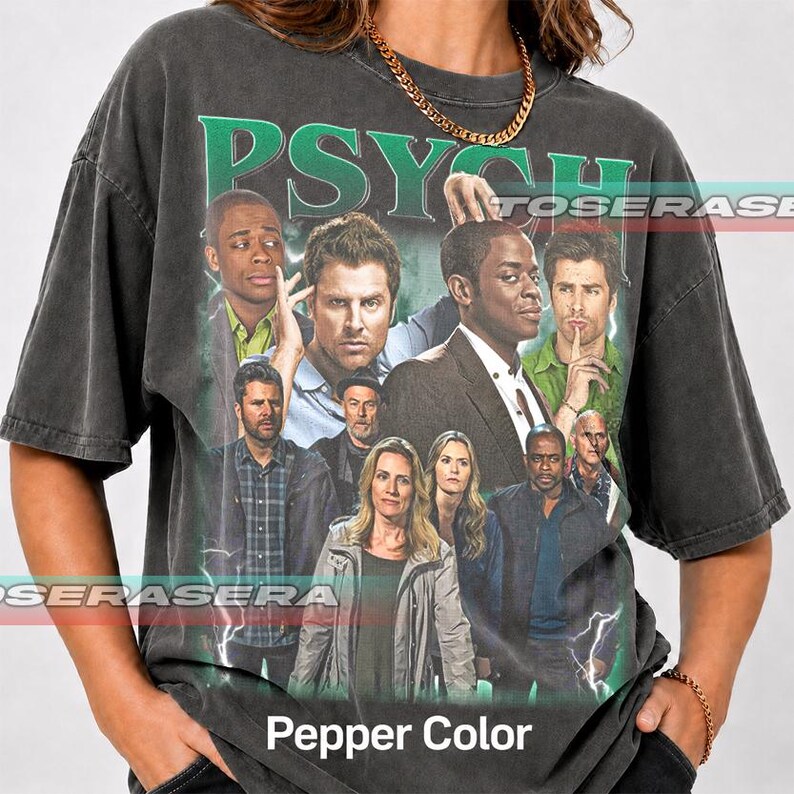 May include: A charcoal gray short-sleeve t-shirt featuring a graphic print of the cast from the television show Psych. The design includes the word Psych in large green letters at the top and a collage of characters in various outfits.