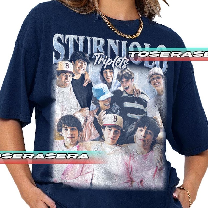 May include: Navy blue t-shirt featuring a graphic of the Sturino Triplets. The graphic includes a group photo of the triplets with the text "STURNIOLO Triplets" in a stylized font. The shirt is a relaxed fit.