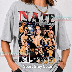 May include: A grey t-shirt featuring a large graphic print of mixed martial artist Nate Diaz. The design includes multiple action photos of the athlete, the text NATE DIAZ in bold red and black lettering, and the number 209 in large gold font.