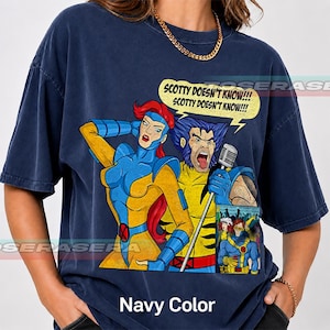 May include: A navy blue t-shirt featuring a graphic print of two comic book characters, one with red hair and one with blue hair, singing into a microphone. The speech bubble contains the text "SCOTTY DOESN'T KNOW!!! SCOTTY DOESN'T KNOW!!!" and a smaller inset image shows two other characters.