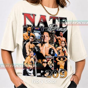 May include: An off-white short-sleeve t-shirt featuring a large graphic print of Nate Diaz. The design includes multiple images of the fighter in action, the text NATE DIAZ in bold red and black lettering, and the number 209 in large gold font.