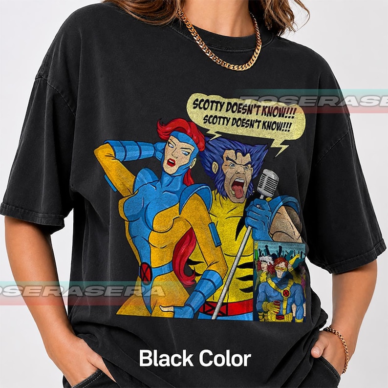 May include: A black t-shirt featuring a graphic print of two comic book characters, one with red hair and one with blue hair, singing into a microphone. A speech bubble above them contains the text, "SCOTTY DOESN'T KNOW!!! SCOTTY DOESN'T KNOW!!!".