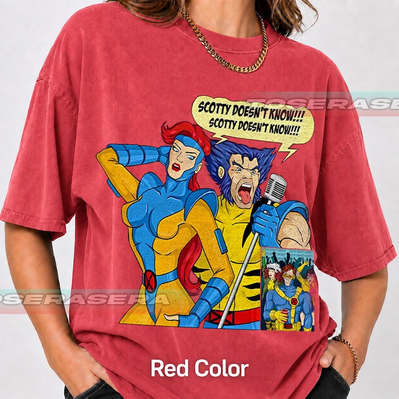 May include: A red short-sleeve t-shirt featuring a graphic of two comic book characters, one with red hair and one with blue hair, singing into a microphone. A yellow speech bubble above them contains the text, SCOTTY DOESN'T KNOW!!!