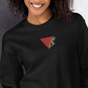 Peut inclure: Sweat-shirt noir avec un triangle rouge et un motif de feuilles vertes.