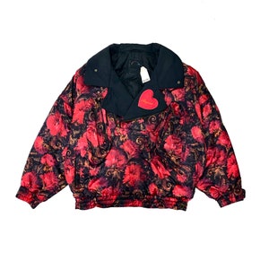 Puede incluir: Una chaqueta de estampado floral negro y rojo con una cremallera negra y una etiqueta de corazón rojo que dice "Soigner".