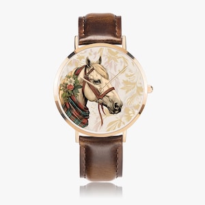 Puede incluir: Reloj de pulsera dorado con correa de cuero marrón. La esfera del reloj presenta una ilustración detallada de la cabeza de un caballo adornada con flores y una bufanda a cuadros sobre un fondo floral crema. El reloj tiene agujas doradas.