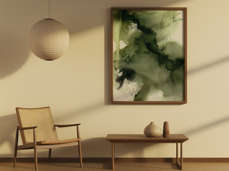 May include: A minimalist living room with a wooden chair, a coffee table, and a framed abstract painting with green and black watercolor washes. A round paper lantern hangs from the ceiling.