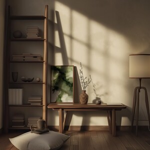 May include: A wooden bench with a vase of dried branches and a framed abstract painting with green and white colors. The bench is in a room with a wooden floor and a bookshelf with books and decorative objects.