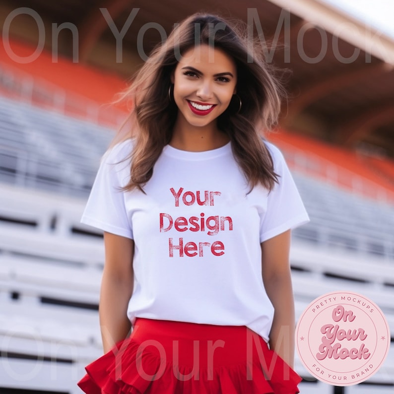 May include: A white t-shirt with the text "Your Design Here" in red. The shirt is being worn by a person standing in front of a white bleacher. The person is wearing a red skirt. A red circle with the text "On Your Mock" is in the lower right corner of the image.