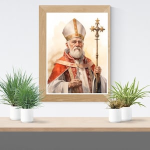 Op de afbeelding: Een ingelijst aquarel schilderij van een man die een rood-witte bisschopskleed en een mitra draagt. Hij houdt een gouden staf met een kruis bovenaan vast. Het schilderij is tegen een witte achtergrond.