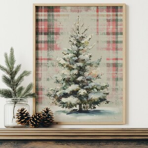 May include: A framed print of a snow-covered Christmas tree. The artwork features a plaid background in red, green, and white. The tree is painted in shades of green and white, with snow covering its branches. The print is displayed on a wooden mantel.