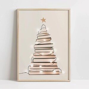 May include: A framed print of a Christmas tree made of stacked books with white lights strung around them. The tree is on a light beige background.