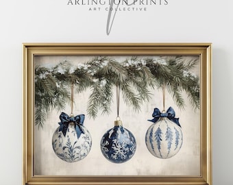 May include: Framed print featuring three Christmas ornaments with blue bows, hanging from a snow-covered evergreen branch. The ornaments have white and blue patterns. The text "ARLINGTON PRINTS ART COLLECTIVE" is at the top.