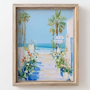 May include: Framed painting depicting a beach scene. A pathway leads to the sea, flanked by white walls and vibrant flowers. Palm trees and a sign reading "To the Beach" are set against a blue sky.
