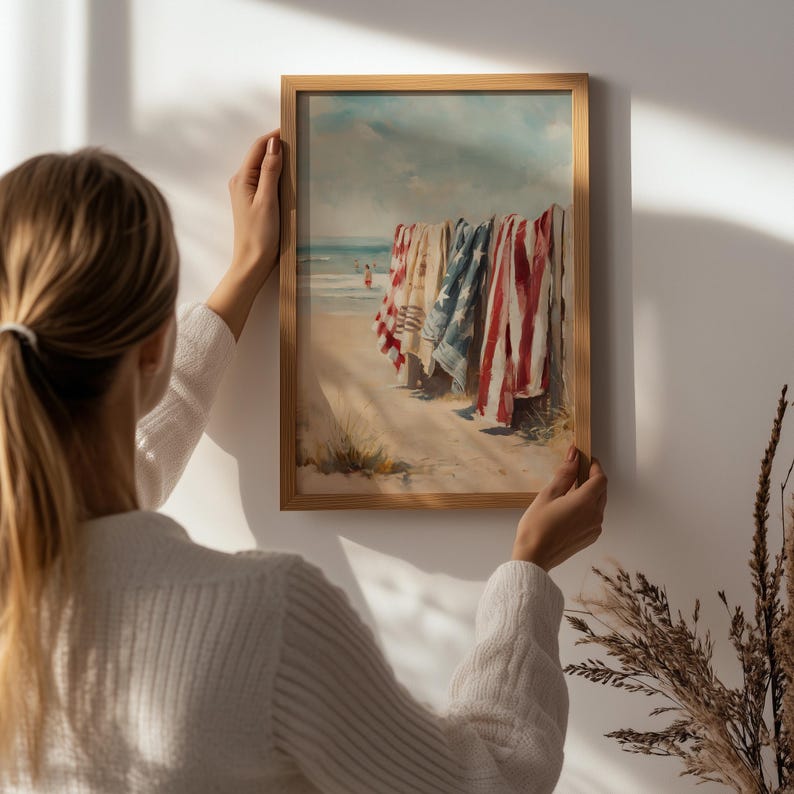 Beach scene with red, white, and blue towels hanging on a wooden fence, ocean waves and swimmers in the background. Coastal Americana style perfect for summer or 4th of July decor. Patriotic Beachy Wall Art, Coastal 4th of July PRINTABLE, Red White Blue Beach Towels, Vintage Summer Seaside Decor, Retro Americana Print