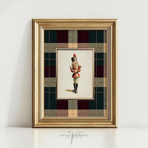May include: A framed print featuring a vintage illustration of a toy soldier in a red and gold uniform, black boots, and a tall black hat. The print is set against a plaid background in shades of green, burgundy, and tan, within a gold frame.
