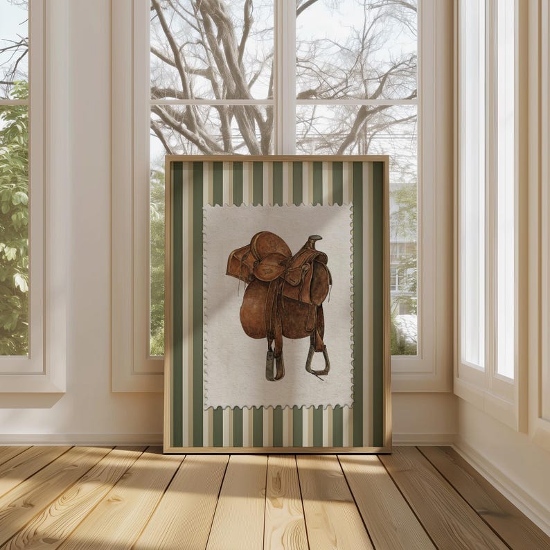 Printed Western wall art featuring a detailed illustration of a vintage leather cowboy saddle with stirrups, displayed on textured parchment-style paper with a striped green and cream background. Ideal for rustic home decor, ranch houses, barns, or cowboy-themed rooms. This artwork evokes classic Western heritage and equestrian charm, making it a perfect printed piece for lovers of country and cowboy style.