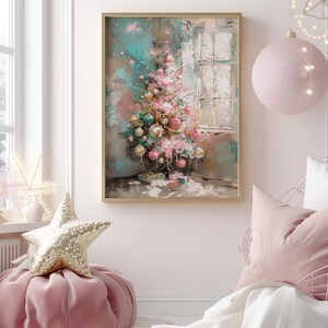 May include: A framed painting of a pink and green Christmas tree with ornaments, set against a light blue and white background. The painting is in a gold frame and is hanging on a white wall.