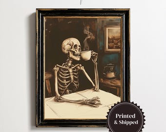 May include: A framed art print featuring a skeleton sitting at a table, holding a steaming white cup. The scene is rendered in dark, muted tones with a black background, a wooden table, and a small framed picture hanging on the wall behind.