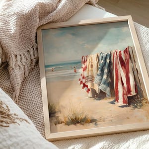 Beach scene with red, white, and blue towels hanging on a wooden fence, ocean waves and swimmers in the background. Coastal Americana style perfect for summer or 4th of July decor. Patriotic Beachy Wall Art, Coastal 4th of July PRINTABLE, Red White Blue Beach Towels, Vintage Summer Seaside Decor, Retro Americana Print