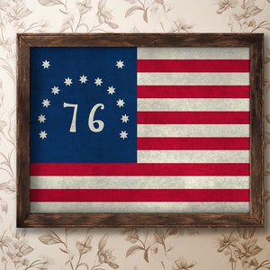 May include: A framed print of the 1776 flag of the United States, featuring 13 red and white stripes and a blue canton with 13 white stars and the number "76" in white.