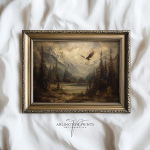 May include: A framed landscape painting featuring a mountain range, a lake, and evergreen trees. An eagle is flying in the sky. The frame is gold-colored with ornate detailing. The text "ARLINGTON PRINTS ART COLLECTIVE" is at the bottom.