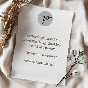 May include: A white artwork print with a torn edge, featuring text that reads "artwork printed on premium long-lasting archival paper." The paper weight is 189 g/m. A small gray circle with a script logo is at the top.