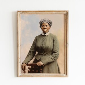 May include: Framed portrait of a woman in a green dress and head covering, resting her arm on a wooden chair. The portrait has a vintage aesthetic with a soft, colorful background. The frame is a light, distressed wood.