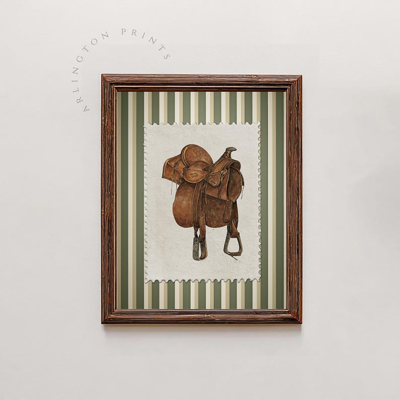 May include: A framed print showing a watercolour illustration of a brown leather saddle. The saddle is on a postage stamp-style background with a green and white striped pattern. The frame is dark brown, and the text "ARLINGTON PRINTS" is visible.